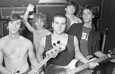 Black-and-white group photo of SS Decontrol posing with their guitars and bass in front of a wall of Marshall amplifiers.