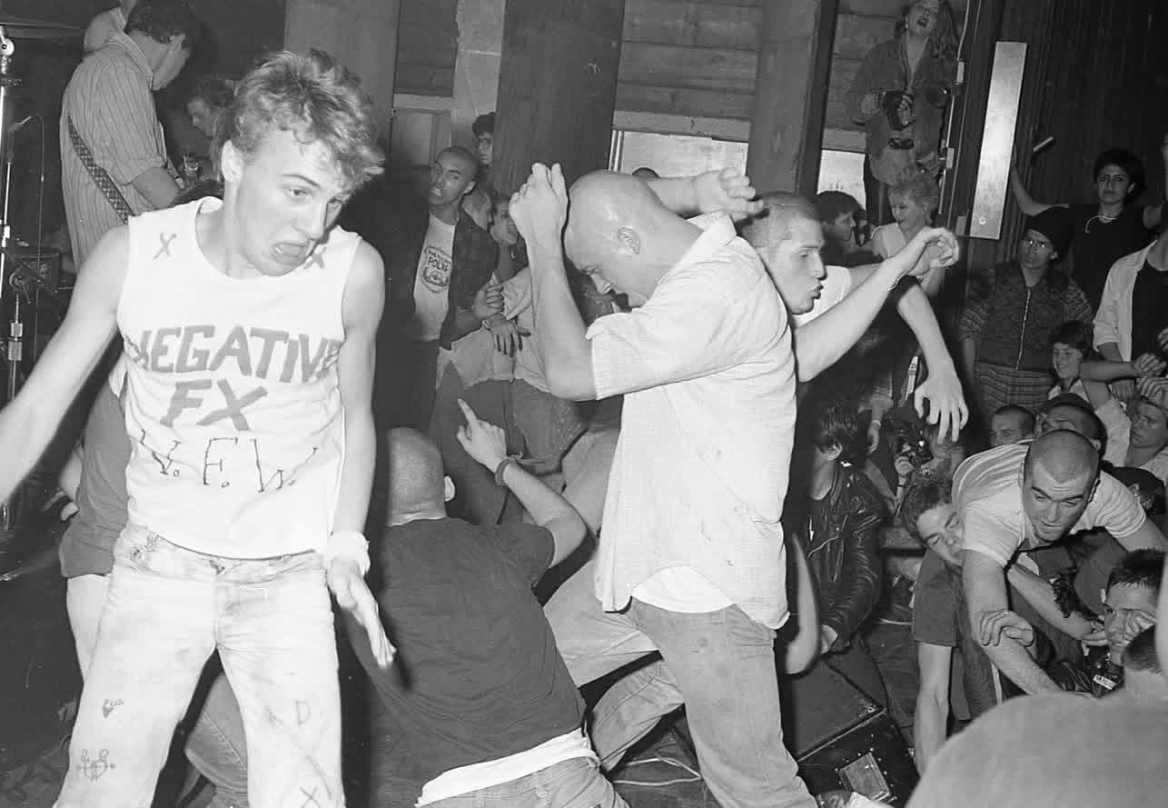 Dancers in the pit at an SSD show, one wearing a Negative FX shirt, with the crowd packed in around them.