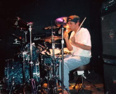 GAGE's drummer playing his kit in a backwards cap.